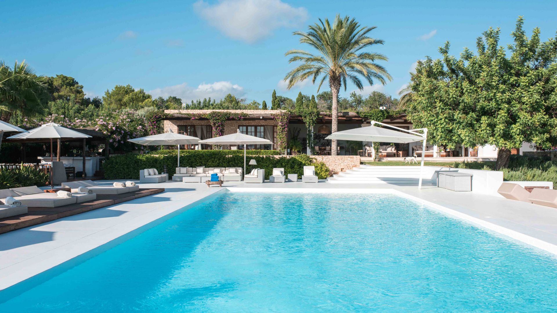 Turquoise Pool with White Sun Decks, Daybeds and Parasols Beside the Stone Villa