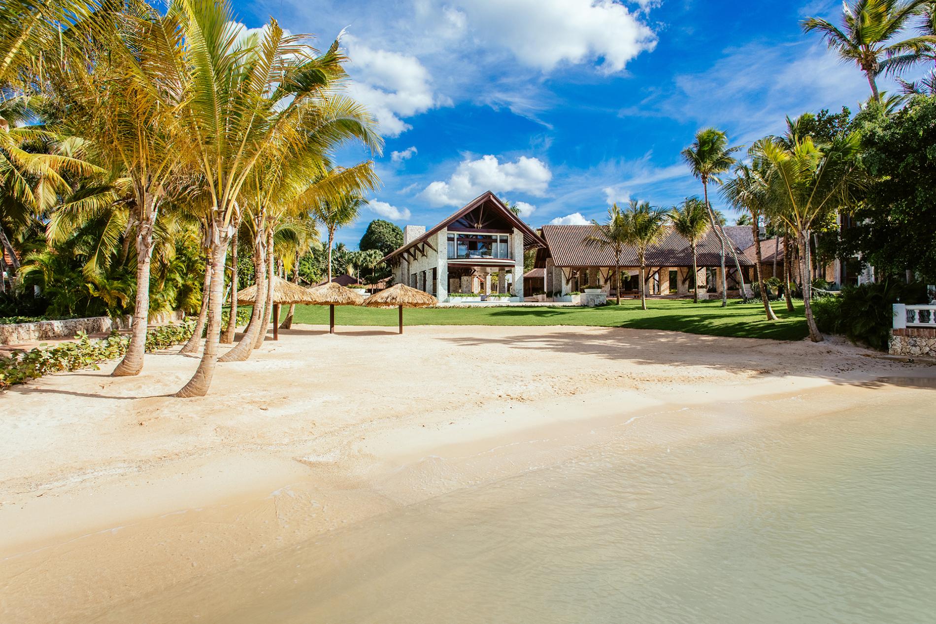 Private beachfront estate with palm trees and thatched umbrellas on Minitas Bay