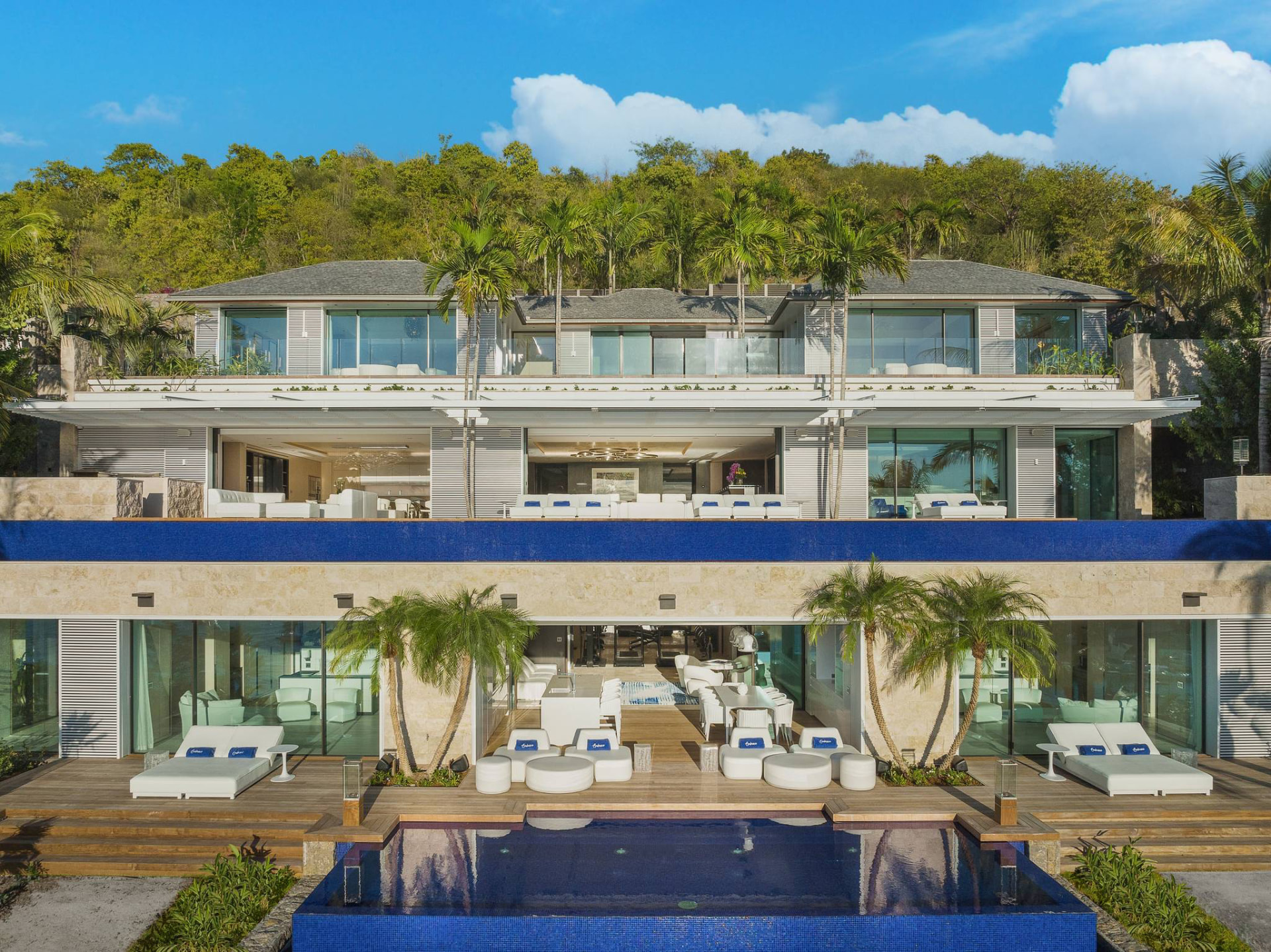 Front exterior of the multi-level St. Barths villa with infinity pool and tropical hillside
